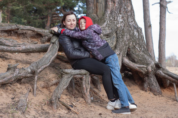 hugging a young mother and son sitting on the roots of trees washed with water