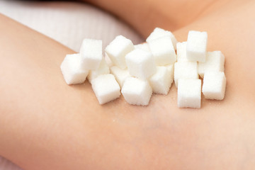 Sugar cubes on armpit of woman. Concept of epilation