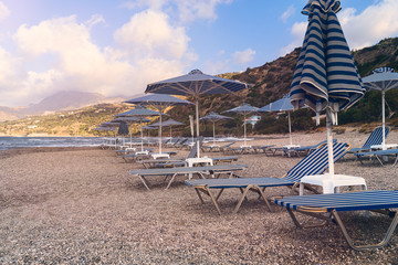 Parasols and empty sun beds on a stone beach