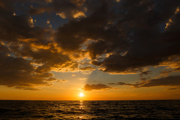 Seascape at Sunset time with nimbus clouds showing the orange sky in low light.