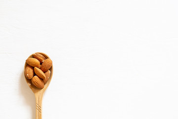 Nut almonds in a wooden spoon on a white background. Natural protein.