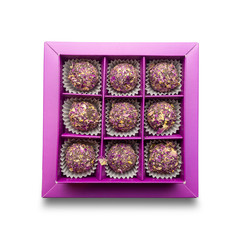 Top view of purple box with round sweets sprinkled with dry rose petals