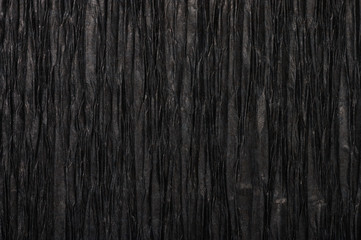 Background of black pressed corrugated paper with a vertical  texture taken close up