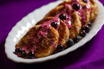Cottage cheese pancakes with blueberries poured with yogurt and with honey on white plate. Delicious Homemade Cheese Pancake. Healthy homemade traditional Ukrainian dishes.
