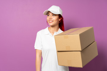 Teenager delivery girl isolated on purple background happy and smiling