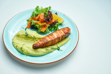 Delicious grilled salmon steak filet with peas in a creamy sauce in a blue plate on a grey background. Tasty seafood