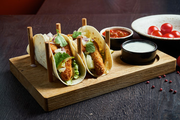 Appetizing Mexican tacos with fried chicken, cabbage, onions and parsley in special stands. Traditional mexican cuisine