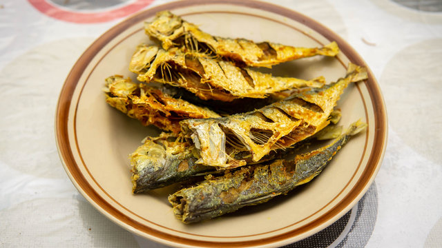 Close up view of fried mackerel fish serve in a plate on a table background.