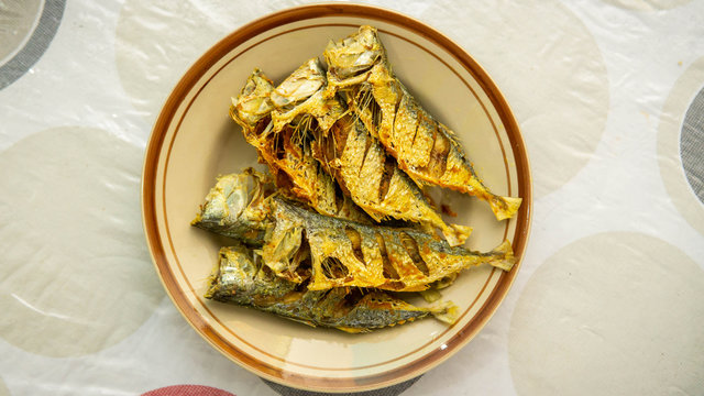 Close up view of fried mackerel fish serve in a plate on a table background.
