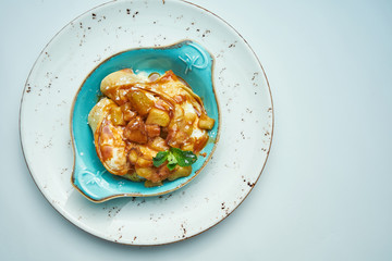 Close up view on tasty French crepes stuffed with cottage cheese and yellow jam in a ceramic plate on grey. ukranian pancakes