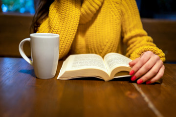 The woman at the table drinking coffee and reading a book-Close Up