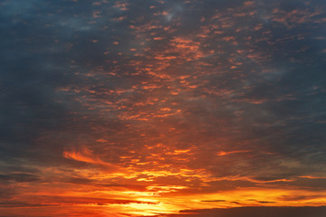Naklejka na ściany i meble Dramatic colorful sunset or sunrise sky landscape. Natural beautiful dark blue to orange dawn background wallpaper. Twilight time cloudscape. Backlit colorful dusk scene