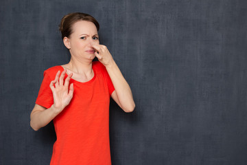 Portrait of displeased young woman pinching her nose with hand