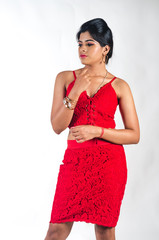 Young woman in a bright red dress standing and looking down to her right and thinking deeply