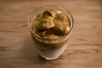 Iced Dalgona Coffee, a trendy korean style  cremy whipped coffee on fresh milk, on wooden background