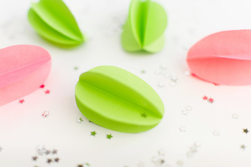 Handmade paper green and pink eggs against of silver stars on white background. Happy Easter background. DIY concept.