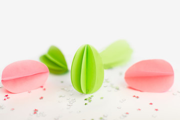 Handmade paper green and pink eggs against of silver stars on white background. Happy Easter background. DIY concept. Copy space.