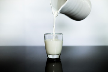 Pouring milk from a white jar into a glass