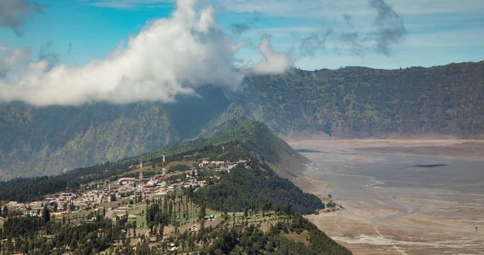 Timelapse of the landscape that opens at the gates of the Tengger massif, and the Bromo volcano, with its caldera and sea of sand, in front of the small town of Cemorolawang, in East Java, Indonesia.