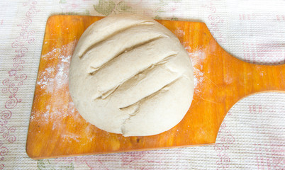 Preparation of dough for baking bread on a light brown wooden board and a board on a checkered white towel. Do-it-yourself baking bread at home from flour