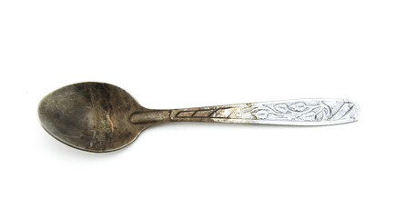 A teaspoon blackened from tannin. On a white isolated background. Black and dirty spoon from tea.