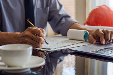 Architect man or male engineer hand writing and sign cheque book, work on laptop computer with...