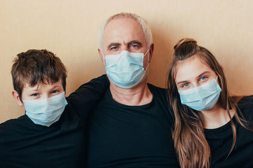 grandfather in face mask with grandchildren look at the camera on yellow background and in diplomacy think about the consequences of coronavirus.Isolated during quarantine due to coronavirus epidemic. - 336446227