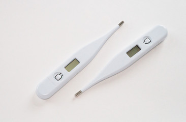 Two white electronic thermometers on a white background