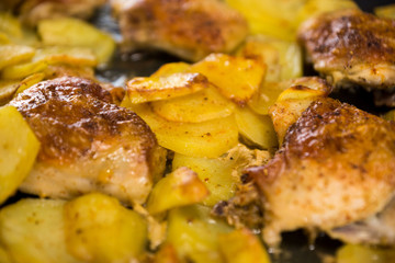 Close-up of fried chicken and potatoes, some objects out of focus. Home cooking