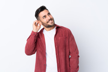 Young handsome man with beard wearing a corduroy jacket over isolated white background thinking an idea