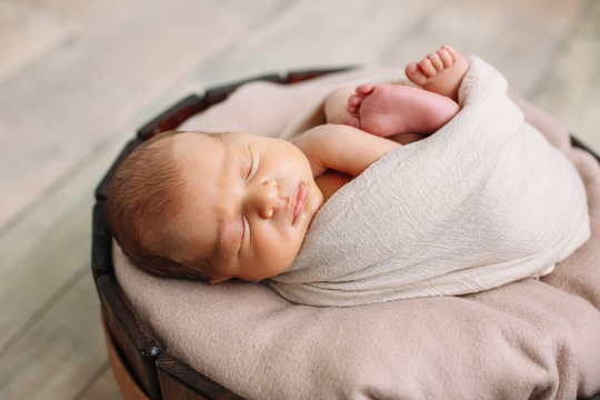 
Newborn baby boy, in the photo the baby is 7 days old from birth, wrapped in a wrapping, sleeps sweetly in a basket