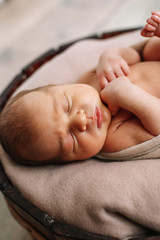 Newborn baby boy, in the photo the baby is 7 days old from birth, wrapped in a wrapping, sleeps sweetly in a basket