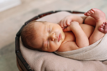 
Newborn baby boy, in the photo the baby is 7 days old from birth, wrapped in a wrapping, sleeps sweetly in a basket