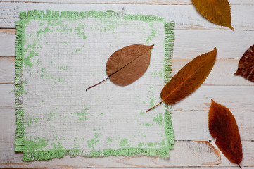 .A canvas napkin and tree leaves lying on a wooden surface. Background for fall and natural objects.