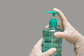 Hand in white glove holding bottle of sanitizer gel.