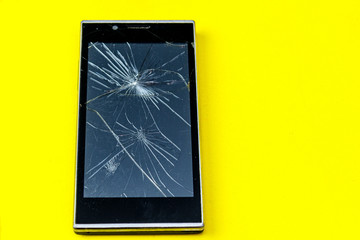 Broken smartphone on a yellow background. Smashed by a fallen phone.