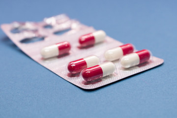 Opened packaging with capsules on a blue background. Isolated. Side view.