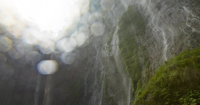 Timelapse of Sewu waterfalls, Java, Indonesia. The camera lens fills with water while a sea of droplets flies through the air, producing a vibrant, lens-blur image.