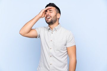Young handsome man with beard over isolated blue background laughing
