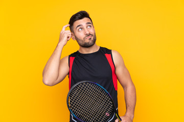 Tennis player man over isolated yellow wall having doubts and with confuse face expression