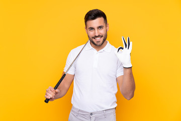 Man over isolated yellow background playing golf making OK sign