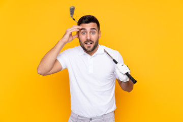 Golfer player man over isolated yellow background with surprise and shocked facial expression