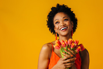 Portrait of a happy smiling young woman with orange tulips bouquet looking up