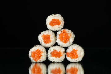 Delicious sushi rolls on black mirror background. Japanese food