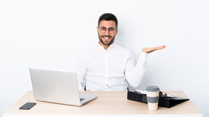 Young businessman in a workplace holding copyspace imaginary on the palm to insert an ad