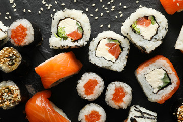 Delicious sushi rolls on black background, top view. Japanese food
