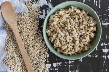 Top view of pearl barley in bowl on the wooden background