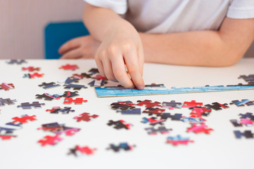 The child collects a puzzle. The development of fine motor skills and intelligence. Children's hands during the game. Home leisure.