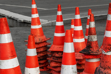 Striped orange cones on the asphalt road. Plastic orange cone on the road. traffic cone, with white and orange stripes on gray asphalt