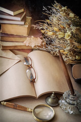 Glasses in an unwritten letter, old pen in an inkwell for a manuscript. Books and a dried flower bouquet. Vintage nostalgia concept